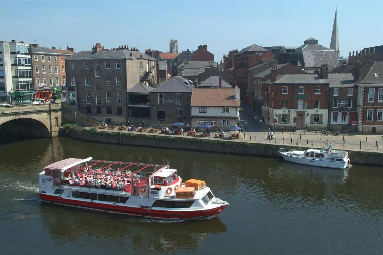 A group of people on a boat on the River Ouse near The Queens Hotel & Victoria Cloisters Apartments in York